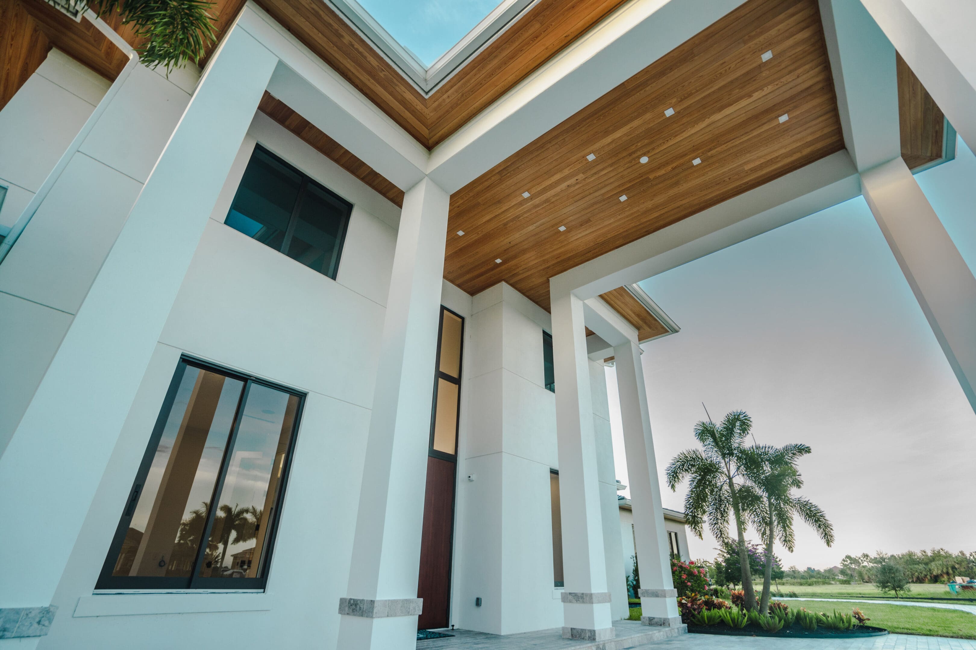 A large white house with a skylight and palm trees.